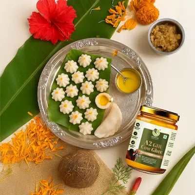 Decorative dish with flowers, a jar of ghee, and a coconut on a white background