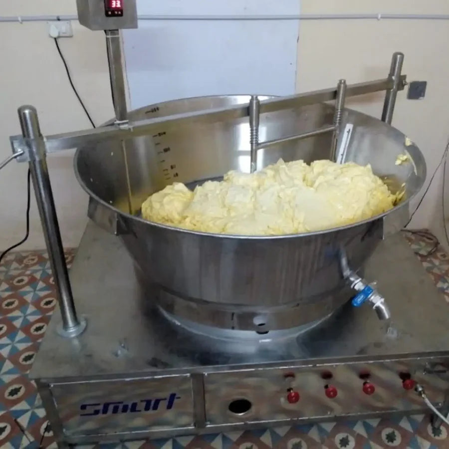 Butter preparation setup featuring a large stainless steel machine filled with freshly churned butter.