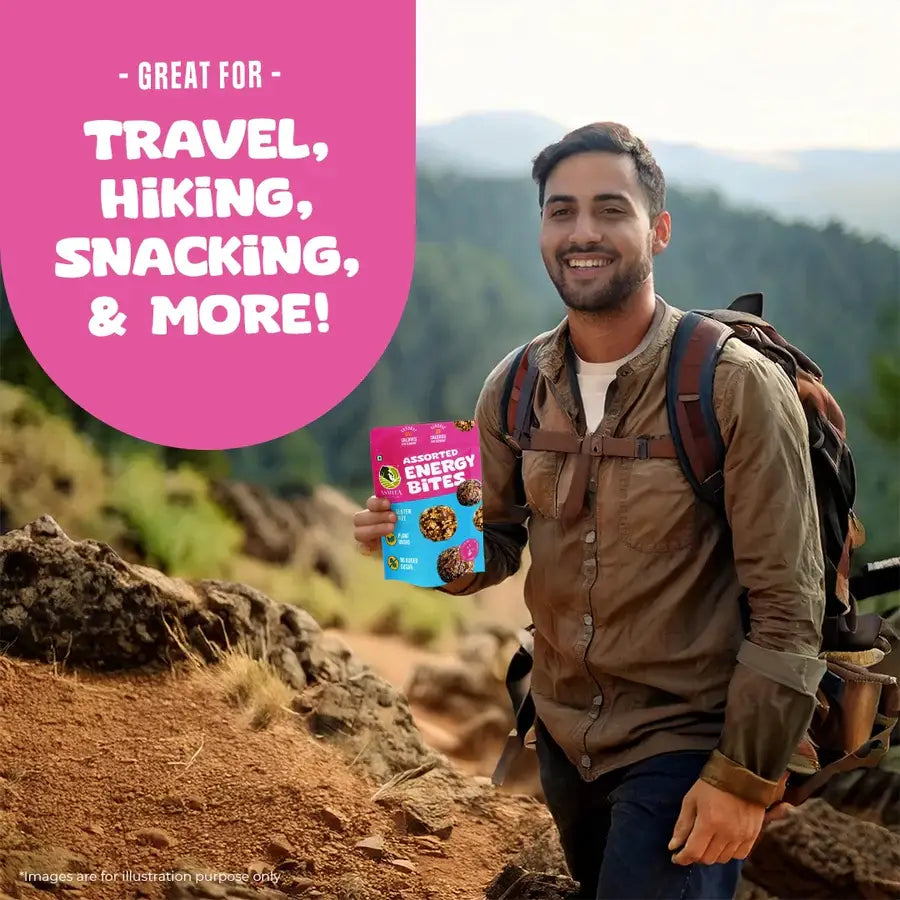 Smiling man hiking outdoors holding Assorted Energy Bites pack, promoting travel, hiking, snacking, and on-the-go energy.