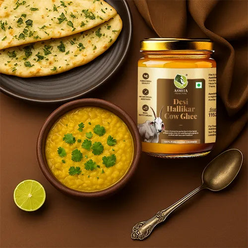 Jar of Devi Hallikar Cow Ghee with a bowl of yellow dal, naan bread, and a lime on a brown background.