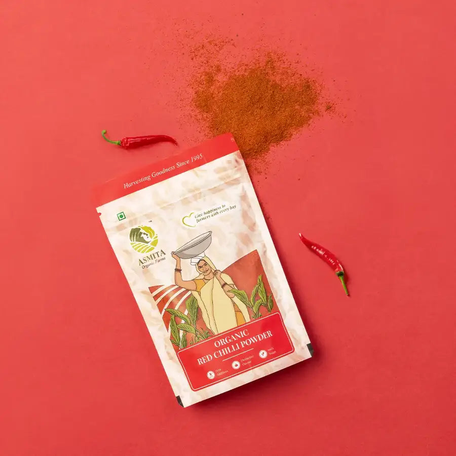  Organic red chili powder packet with chili peppers and powder spilled on a red background.