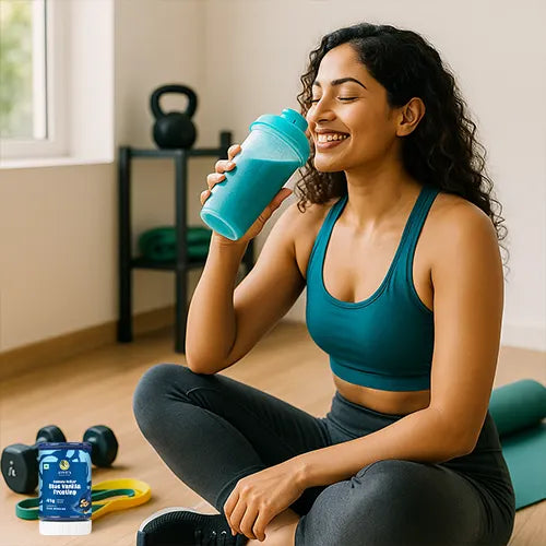 Woman in a gym setting holding a blue vennila frosting  shake