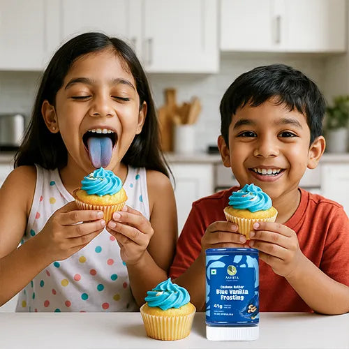 Two children enjoying cupcakes with blue venilla frosting in a kitchen setting.