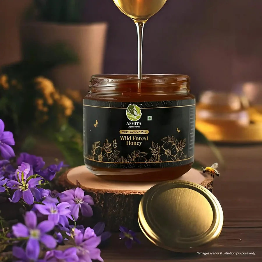 A jar of Asmita Organic Farms Wild Forest Honey with golden honey dripping into the jar, surrounded by flowers.